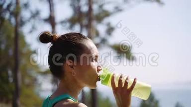 漂亮的女孩慢跑后从塑料瓶里喝水。